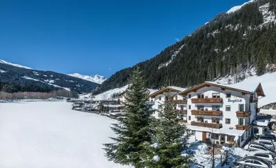 a hotel in the mountains with a snow covered field at Hotel Bergblick in Racines