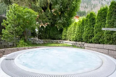 a large pool in a garden with trees at Hotel Bergblick in Racines