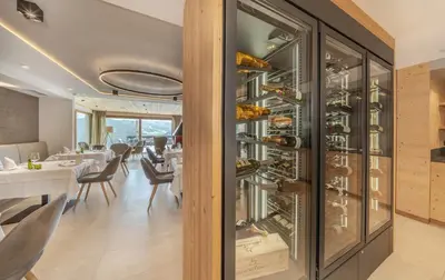 a dining room with white tables and chairs and windows at Nature Hotel Delta in Colfosco