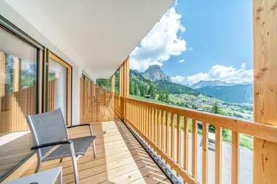 a chair on a balcony with a view of mountains at Nature Hotel Delta in Colfosco