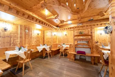 a restaurant with wooden walls and tables and chairs at Hotel Laurin in Canazei