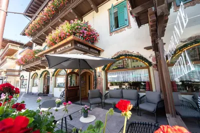 a patio with chairs and an umbrella and flowers at Hotel Laurin in Canazei