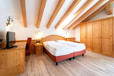 a bedroom with a bed and a desk and a tv at Hotel Laurin in Canazei