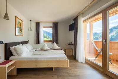a bedroom with a bed and a large window at Declara B&B and apartaments in Colfosco