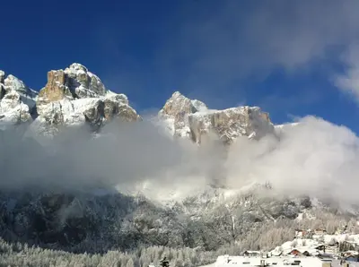 a snow covered mountain with clouds in front of it at Declara B&B and apartaments in Colfosco