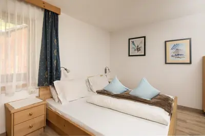 a bedroom with a bed with white and blue pillows at Declara B&B and apartaments in Colfosco