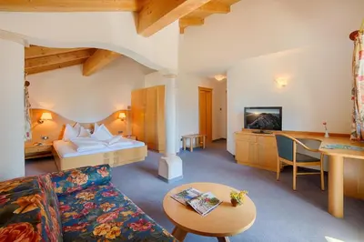 a living room with a couch and a bed at Hotel Gissbach in Brunico