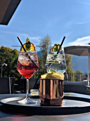 a table with two cocktails and a basket of pickles at Hotel Gissbach in Brunico