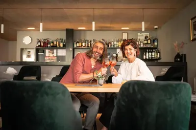 a man and woman sitting at a table with glasses of wine at Hotel Gissbach in Brunico