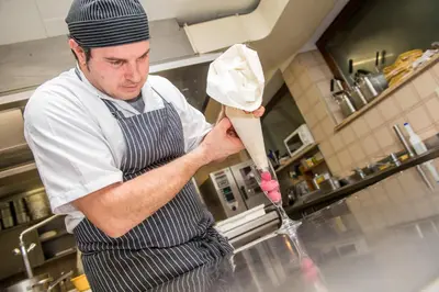 a man in a kitchen preparing food on a counter at Hotel Gissbach in Brunico