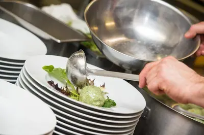 a person serving a plate of food on a counter at Hotel Gissbach in Brunico