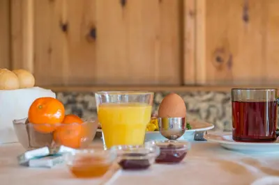 a table with two glasses of orange juice and eggs at Hotel Gissbach in Brunico