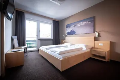 a bedroom with a large bed and a large window at Hotel Gissbach in Brunico