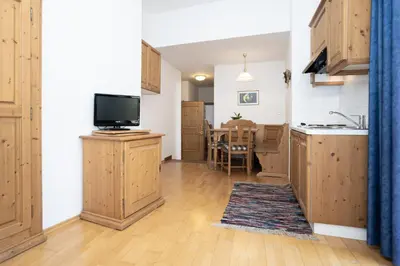a kitchen with wooden cabinets and a tv and a table at Appartements Eppanerhof in Appiano sulla Strada del Vino