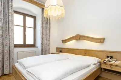 a bedroom with a bed with white sheets and a chandelier at Appartements Eppanerhof in Appiano sulla Strada del Vino