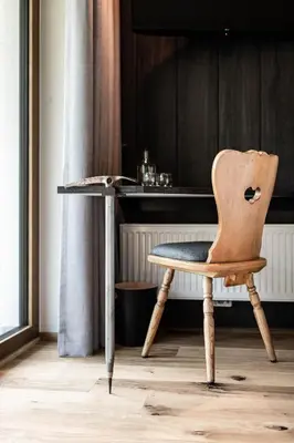 a wooden chair sitting in front of a desk at Hotel Wochtla Buam Aktivhotel am Kronplatz mit Sauna in Brunico