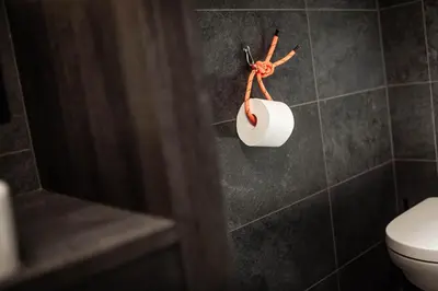 a roll of toilet paper on a holder in a bathroom at Hotel Wochtla Buam Aktivhotel am Kronplatz mit Sauna in Brunico