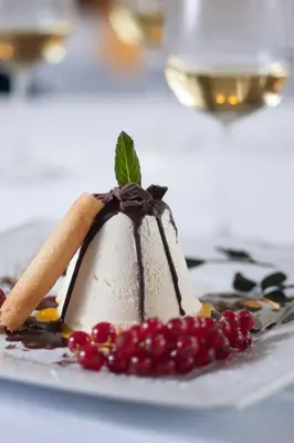 a dessert on a white plate with berries on it at Hotel Wochtla Buam Aktivhotel am Kronplatz mit Sauna in Brunico