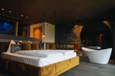 a bedroom with a large bed and a chair at Hotel Wochtla Buam Aktivhotel am Kronplatz mit Sauna in Brunico