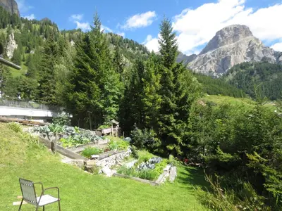 a bench in a garden with mountains in the background at Hotel Borest in Colfosco