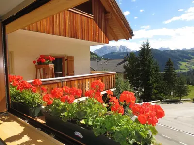a balcony with red flowers on a house at Hotel Borest in Colfosco