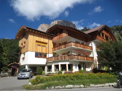 a building with a balcony with a mountain in the background at Hotel Borest in Colfosco