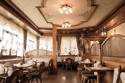 a restaurant with tables and chairs and a ceiling at Albergo Centrale in San Martino di Castrozza