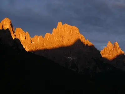 a group of mountains with the sun shining on them at Albergo Centrale in San Martino di Castrozza