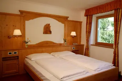 a bedroom with a bed with a wooden headboard and a window at Residence Riposo in Colfosco