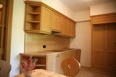 a kitchen with wooden cabinets and a sink and a table at Residence Riposo in Colfosco
