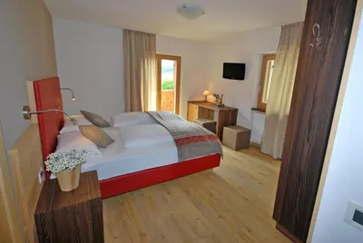 a bedroom with a large bed and a television at Monti Pallidi B&B Apartments in Corvara in Badia
