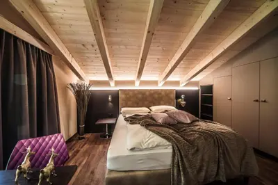 a bedroom with a large bed and wooden ceilings at Monti Pallidi B&B Apartments in Corvara in Badia