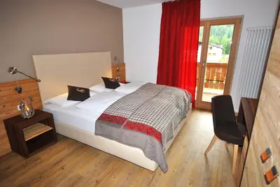 a bedroom with a large bed with a red curtain at Monti Pallidi B&B Apartments in Corvara in Badia
