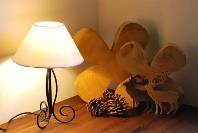 a lamp sitting on a table next to a wooden bird statue at Monti Pallidi B&B Apartments in Corvara in Badia