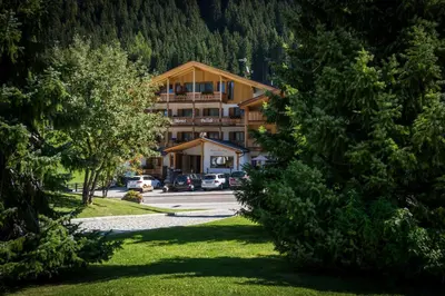 a large building with cars parked in a parking lot at Monti Pallidi B&B Apartments in Corvara in Badia