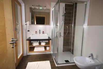 a bathroom with a sink and a glass shower at Monti Pallidi B&B Apartments in Corvara in Badia