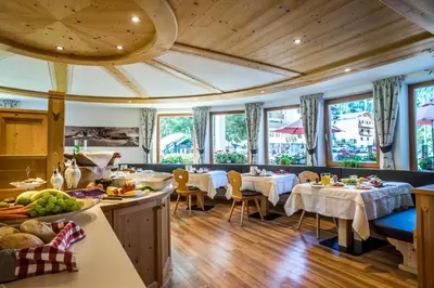 a dining room with tables and chairs and windows at Monti Pallidi B&B Apartments in Corvara in Badia