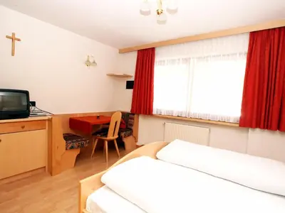 a bedroom with a bed and a desk and a television at Ciasa Parom in San Cassiano