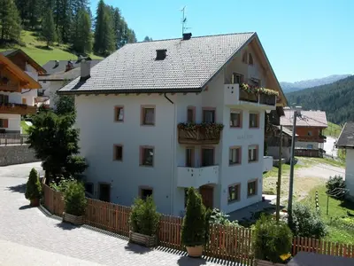 a large white building with a fence in front of it at Ciasa Parom in San Cassiano