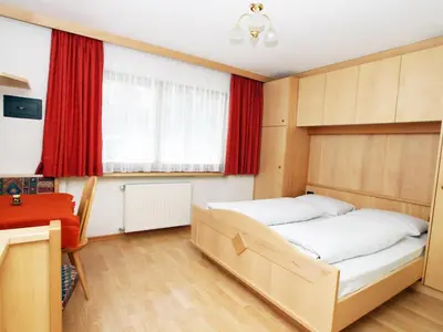 a bedroom with two beds and a window with red curtains at Ciasa Parom in San Cassiano