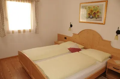 a bedroom with a bed with a wooden headboard and a window at Residence Ciasa Dl Mone in Colfosco