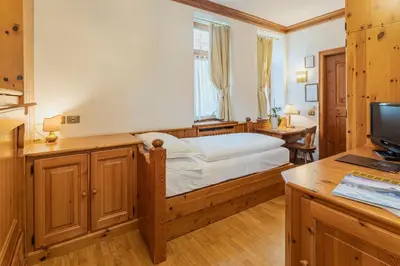 a bedroom with a bed and a desk with a television at Franceschi Park Hotel in Cortina dʼAmpezzo