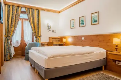 a bedroom with a bed and a desk and a window at Franceschi Park Hotel in Cortina dʼAmpezzo