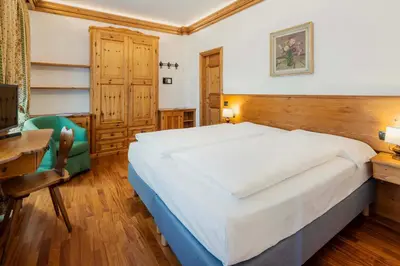 a bedroom with a large bed and a desk at Franceschi Park Hotel in Cortina dʼAmpezzo
