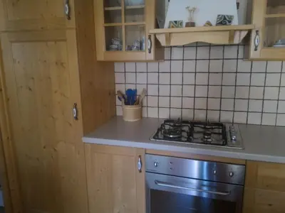 a kitchen with wooden cabinets and a stove top oven at Casa Lausen in Canale San Bovo