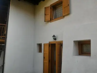 a white building with a wooden door and windows at Casa Lausen in Canale San Bovo