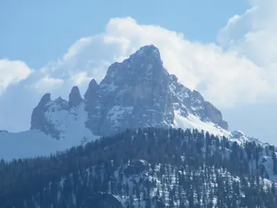 a mountain covered in snow and trees with clouds at Agriturismo Fattoria Meneguto Societa Agricola Semplice in Cortina dʼAmpezzo