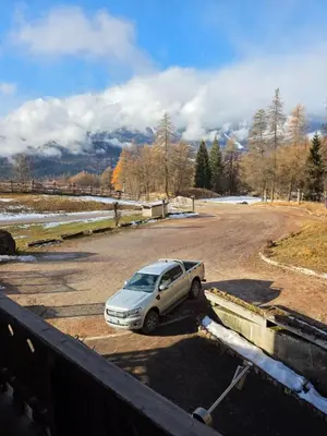 a car parked in a parking lot with mountains in the background at Agriturismo Fattoria Meneguto Societa Agricola Semplice in Cortina dʼAmpezzo