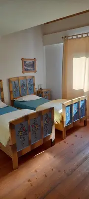 two twin beds in a room with wooden floors at Agriturismo Fattoria Meneguto Societa Agricola Semplice in Cortina dʼAmpezzo