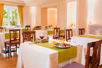 a restaurant with white tables and chairs with wine glasses at Hotel Serena Cortina in Cortina dʼAmpezzo